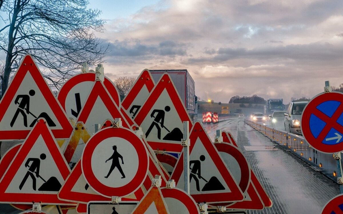 Vor einer Baustelle stehen viele Schilder und Autos im Stau Vor einer Baustelle stehen viele Schilder und Autos im Stau
